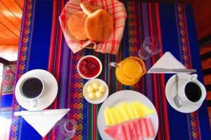 a table topped with plates of food and cups of coffee at Hospedaje Kamila in Cusco