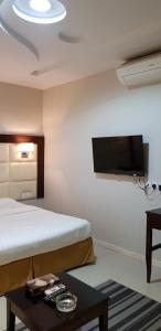 a room with a bed and a table and a tv at Nozul Al Tout Furnished Apartments in Al Kharj