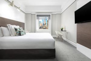 una camera da letto con un grande letto bianco e una televisione di Paramount Hotel Times Square a New York