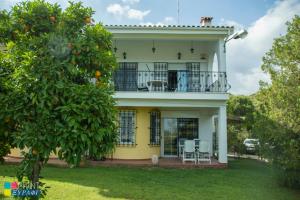 a yellow house with a balcony and an orange tree at The L Villa in Nea Peramos