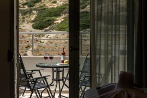 a dining room table with chairs and a window at Matala Bay Hotel & Apartments in Matala