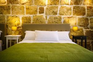 ein Schlafzimmer mit einem grünen Bett und einer Steinmauer in der Unterkunft Regina Elena Rooms in Avola