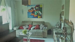 ein Wohnzimmer mit einem Sofa und einem Gemälde an der Wand in der Unterkunft Duplex DE LUX com piscina,Churrasqueira TOTALMENTE PRIVATIVO in Nova Friburgo