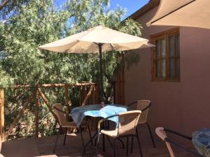 uma mesa e cadeiras com um guarda-sol num pátio em Refugio Don Natu em San Pedro de Atacama