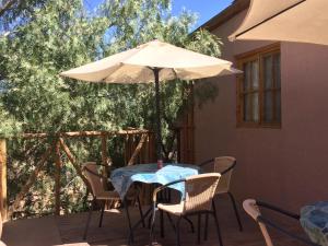 a table and chairs with an umbrella on a patio at Refugio Don Natu in San Pedro de Atacama