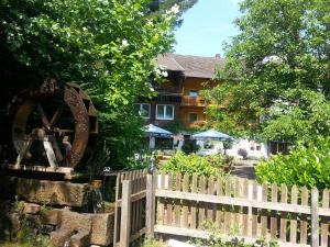 a wooden fence with a woodenmill in front of a house at Landgasthof Linkenmühle in Hornbach