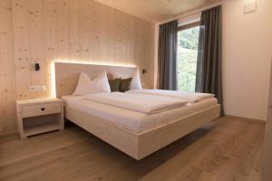 ein Schlafzimmer mit einem großen weißen Bett mit einem Fenster in der Unterkunft Greiterhof in Lana