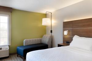 a hotel room with a bed and a chair at Holiday Inn Express & Suites Milton East I-10, an IHG Hotel in Milton