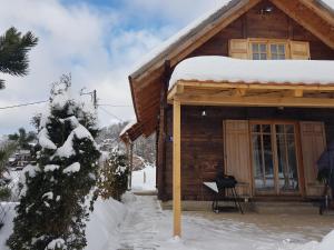 Cabaña de madera con nieve en el techo en Stara Planina Stankovic, en Crni Vrh
