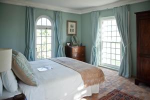 a bedroom with a large bed and two windows at Hawksmoor House in Stellenbosch