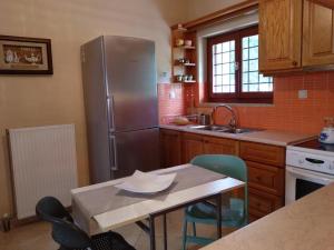 スペツェスにあるKasteli Houseのキッチン(ステンレス製の冷蔵庫、テーブル、椅子付)