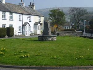 a statue in the grass in front of a house at Causeway Cottage in Cartmel