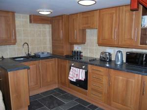 a kitchen with wooden cabinets and black counter tops at Causeway Cottage in Cartmel