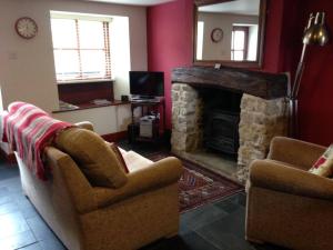a living room with two chairs and a fireplace at Causeway Cottage in Cartmel