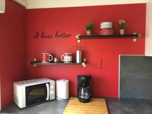 uma cozinha com um micro-ondas e uma parede vermelha em BedinReims cozy apartment parking and wifi free ideal 4 Adultes et 2 Enfants em Reims