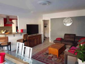 uma sala de estar com um sofá e um relógio na parede em BedinReims cozy apartment parking and wifi free ideal 4 Adultes et 2 Enfants em Reims