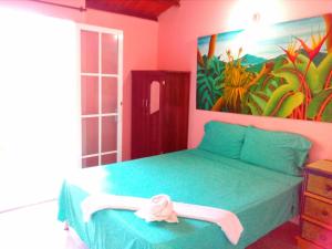 a bedroom with a green bed and a painting on the wall at Casa Del Pintor in Santa Marta