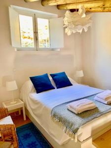 a bedroom with a bed with blue pillows and a window at Casas de Mértola in Mértola