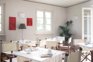 a restaurant with white tables and chairs and windows at Relais Villa Isabel in Pietrasanta