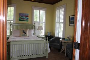 a bedroom with a bed with a chair and windows at Beachview Inn and Spa in Tybee Island