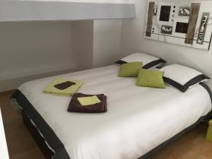a large white bed with green and black pillows at Gîte avec Piscine Lou Minèstraü in Entraigues-sur-la-Sorgue