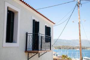 a white building with a balcony with a view of the water at Villa @ Poros in Poros