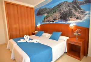 a bedroom with two beds with a painting on the wall at Hotel Portonovo in Portonovo