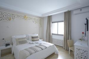a white bedroom with a white bed and a window at Dar Corniche La Marsa (Adults Only) in La Marsa