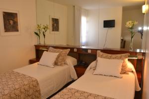 a hotel room with two beds and a television at Hotel de la Cañada in Córdoba