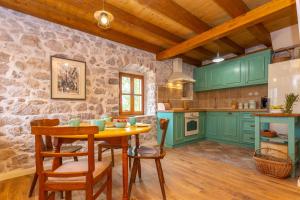 een keuken met groene kasten en een tafel en stoelen bij Rustica house in Skradin