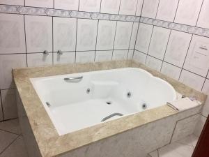 a white bath tub in a white tiled bathroom at Hotel Carpevita in Canela