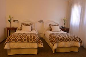 a hotel room with two beds and a window at Hotel de la Cañada in Córdoba
