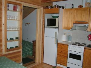 a kitchen with a white refrigerator and a stove at Yll&auml;sriemu Apartments in &Auml;k&auml;slompolo