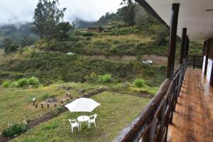 a balcony with two chairs and a white umbrella at CasaNostra Choquequirao in Cachora