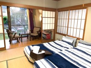een slaapkamer met een bed en een tafel en ramen bij Koto House in Yachiyo