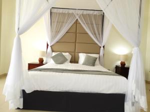 a bedroom with a canopy bed with white curtains at Nyali Golf View Residence in Mombasa