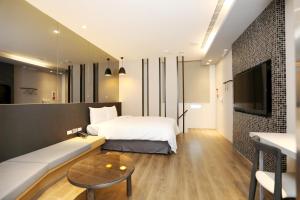 SUNLINE Motel & Resort في بايهة: غرفة نوم بسرير واريكة وتلفزيون