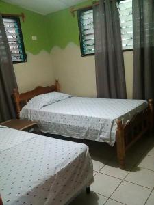 two twin beds in a room with windows at Hostel Sunset Villas Popoyo in Popoyo