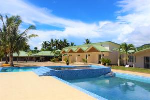 a swimming pool in front of a house at Le Uaina Beach Resort in Falepuna