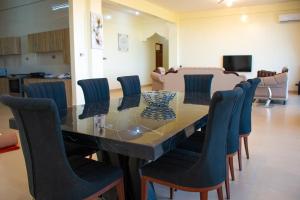 a dining room with a glass table and blue chairs at Nyali Golf View Residence in Mombasa