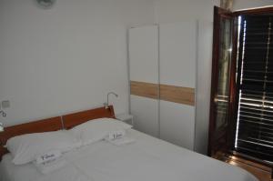 a bedroom with a bed with white sheets and a window at Apartments Olive i Lavender in Mandre