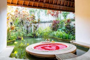 a garden with a fountain in the middle of a pond at Villa Taman di Blayu by Nagisa Bali in Tabanan