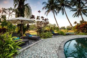 una piscina del complejo con sillas y sombrilla en Villa Taman di Blayu by Nagisa Bali, en Tabanan