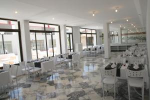 a banquet hall with white tables and chairs and windows at Scala Nuova Annex in Cesme
