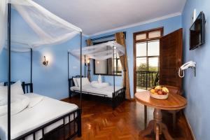 Un dormitorio con 2 camas y una mesa con un bol de fruta en Mrimba Palm Hotel, en Arusha