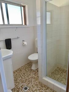 a bathroom with a toilet and a glass shower at Gilgandra Motel in Gilgandra