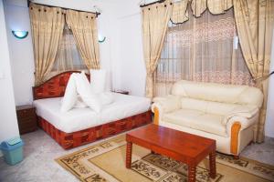 Habitación con 2 camas, sofá y mesa. en Natron Palace Hotel, en Arusha