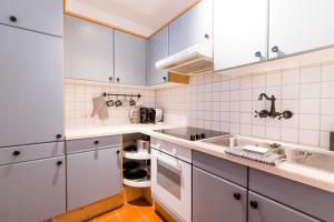 una cocina con armarios blancos y fregadero en MOOKI Mountain & Pool Gerlitzen Apartment, en Kanzelhöhe