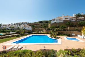einen Pool mit Stühlen und Gebäuden im Hintergrund in der Unterkunft Luxury townhouse La Cala Golf Resort (Golf, Beach, Nature and Amazing views) in La Cala de Mijas