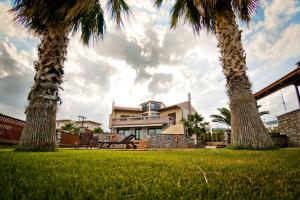 una casa con palmeras y un banco en el césped en Villa Theano, en Agios Nikolaos
